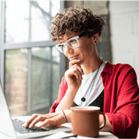 Woman doing online banking with her laptop while drinking coffee.